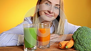 The woman at the table next to the juices and vegetables