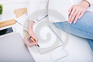 Woman on table writing in notepad