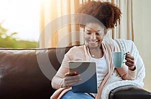 Woman, tablet and drink on sofa in home for reading ebook, online blog and relax with lens flare. Female person, couch