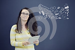 Woman with tablet in front of background with drawn business chart and icons.
