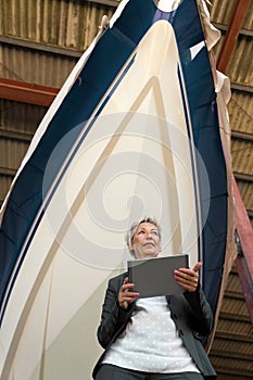 Woman with a Tablet in front of a boat in a shipyard