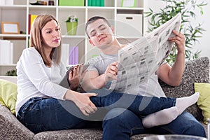 Woman with tablet and husband with newspaper reading news