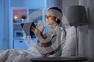 woman with tablet pc in bed has video call