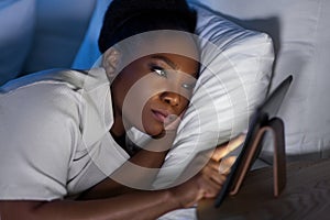 woman with tablet pc in bed at home at night