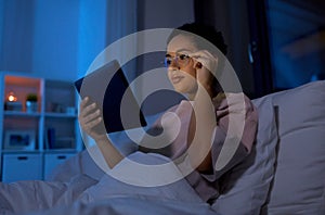 woman with tablet pc in bed at home at night