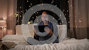 woman with tablet pc in bed at home at night