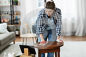 woman with tablet pc cleaning table with tissue