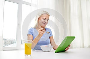 Woman with tablet pc eating breakfast at home