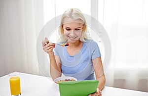 Woman with tablet pc eating breakfast at home