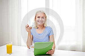 Woman with tablet pc eating breakfast at home