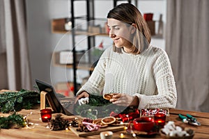 woman with tablet pc makes christmas wreath