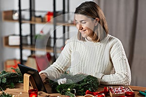 woman with tablet pc makes christmas wreath