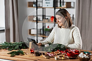 woman with tablet pc makes christmas wreath