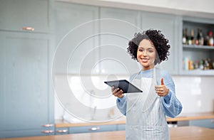 woman with tablet pc showing thumbs up in kitchen