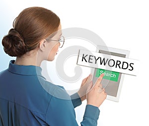 Woman with tablet searching for keywords on background