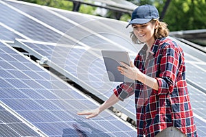 Woman with tablet touching solar panel
