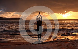 Woman Tadasana - Mountain Pose yoga by the sea at sunrise