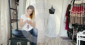 Woman in tailor`s shop with phone