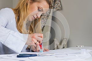 Woman tailor during work on sewing patterns. Seamstress glue together details of paper for dress