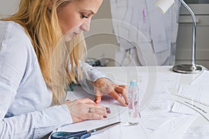 Woman tailor during work on sewing patterns. Seamstress glue together details of paper for dress