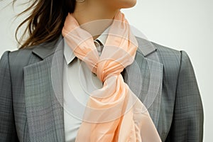 woman in a tailored suit, accessorizing with a peach silk scarf