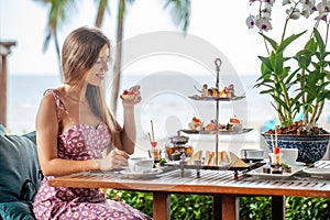 Woman take cake out of afternoon tea set in sea outdoors restaurant photo