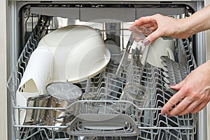 Woman take clean drinking glass from dishwasher machine. woman putts drinking glass to dishwasher machine to clean it photo
