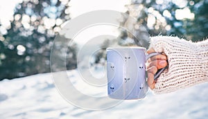 Woman take in hand cup of hot drink. Winter forest glade, bright sunnyday scene photo