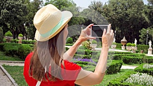 Woman take photo of park on cellphone in slow motion. Female tourist take picture in Villa Borghese