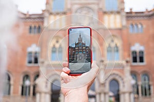 Woman take photograph with smart phone to hystoric building in Barcelona. Traveler, tourism, discover, caucasian female