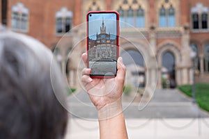 Woman take photograph with smart phone to hystoric building in Barcelona. Traveler, tourism, discover, caucasian female