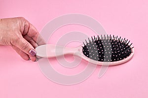 woman take a pink hairbrush isolated on a pink coral background with space. beauty hair accessory for hairstyle