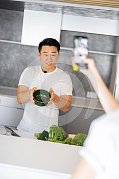 Woman take video on smartphone of man cook salad