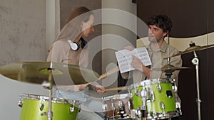 Woman takes drum class and teacher demonstrates music sheet