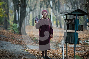 A woman takes a letter out of an old mailbox.