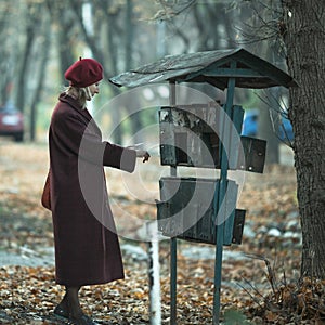A woman takes a letter out of an old mailbox outdoor.