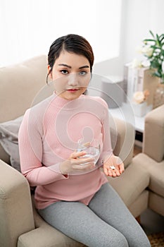Woman takes medicines with glass of water. Daily norm of vitamins