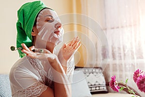 Woman takes off facial sheet mask at home after bath. Healthy skincare routine. Beauty products and cosmetics