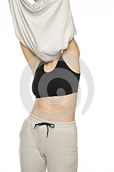 Woman takes off the top of the tracksuit on a white background