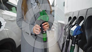 Woman takes out fueling gun from car gas tank after refueling is completed. Slow motion