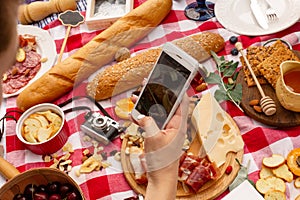 Woman takes a photo on her mobile phone durring outdoor picnic