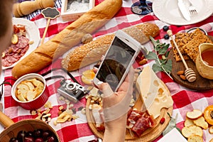 Woman takes a photo on her mobile phone durring outdoor picnic photo