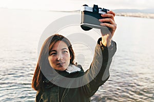 Woman takes photographs self portrait on coastline