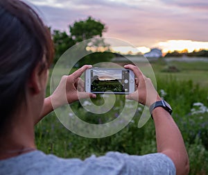 Woman takes picture of sunset on her phone