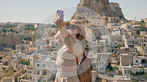 A woman takes a selfie on the background of the city with the Ortahisar fortress