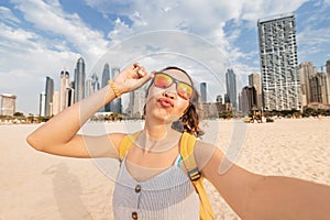 Woman takes a selfie photo against the backdrop of Dubai skyscrapers and parodies inflated lips and duckface
