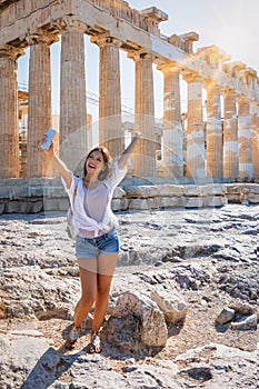 Woman takes selfie pictures in front of the Parthenon Temple at the Acropolis of Athens, Greece