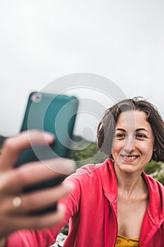 A woman takes a selfie on top of a mountain