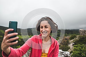 A woman takes a selfie on top of a mountain