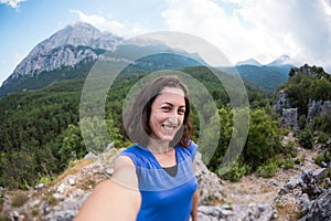 A woman takes a selfie on top of a mountain